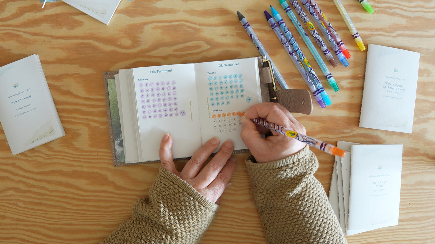 Shows someone marking circles in our aldan media Catholic Bible journey map on a wooden table. The shown Catholic Bible study kit is for Traveler's Notebook Passport size.